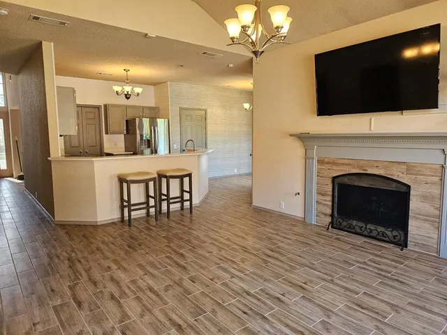a living room with a fireplace a flat screen tv and kitchen view