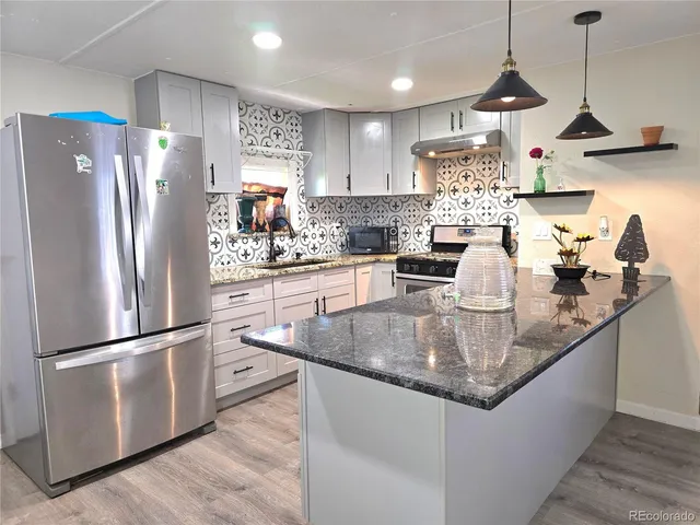 a kitchen with stainless steel appliances granite countertop a refrigerator a sink dishwasher a refrigerator and white cabinets with wooden floor