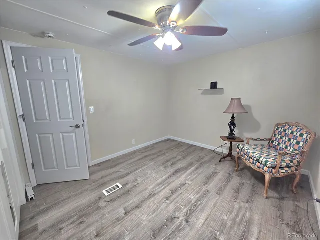 an empty room with wooden floor fan and windows