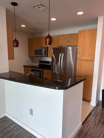 a kitchen with stainless steel appliances kitchen island a refrigerator a stove a microwave oven with wooden floor