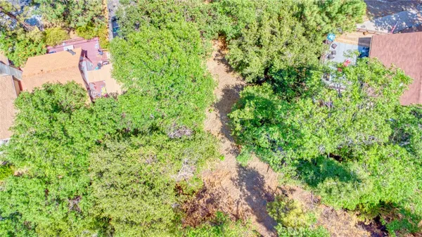 an aerial view of residential house with outdoor space and trees all around
