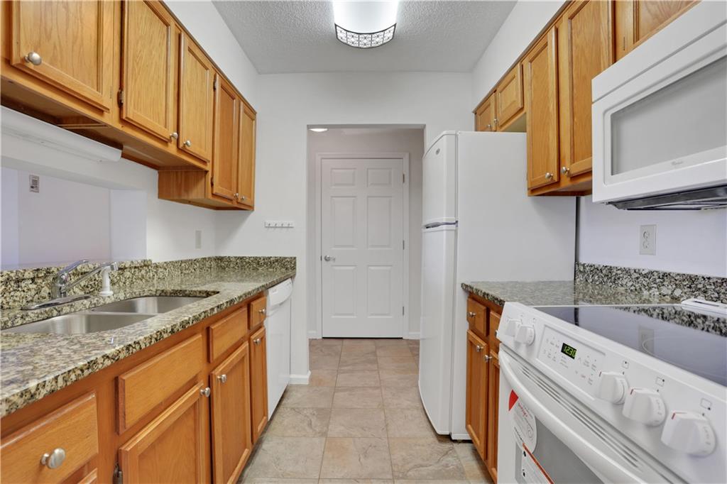 300 Johnson Ferry Road, Unit B1002 Sandy Springs, GA 30328 - Photo 4 of 26 a kitchen with granite countertop a sink and a refrigerator