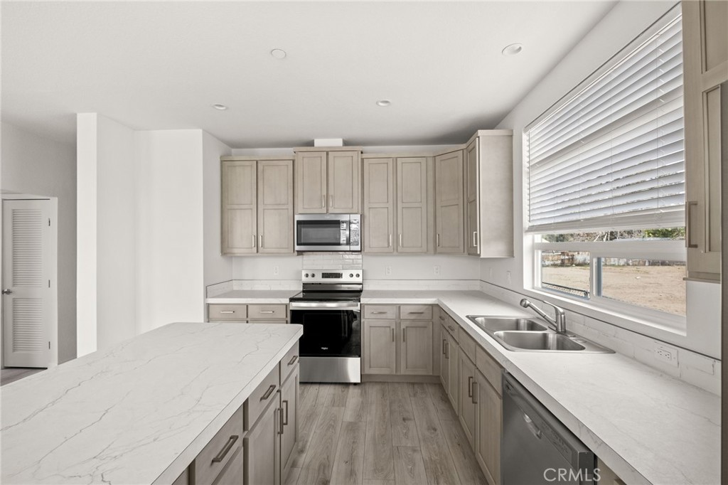 33064 Willard Street Winchester, CA 92596 - Photo 16 of 34 a kitchen with stainless steel appliances a sink a stove a refrigerator cabinets and a window