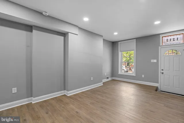 an empty room with wooden floor and windows