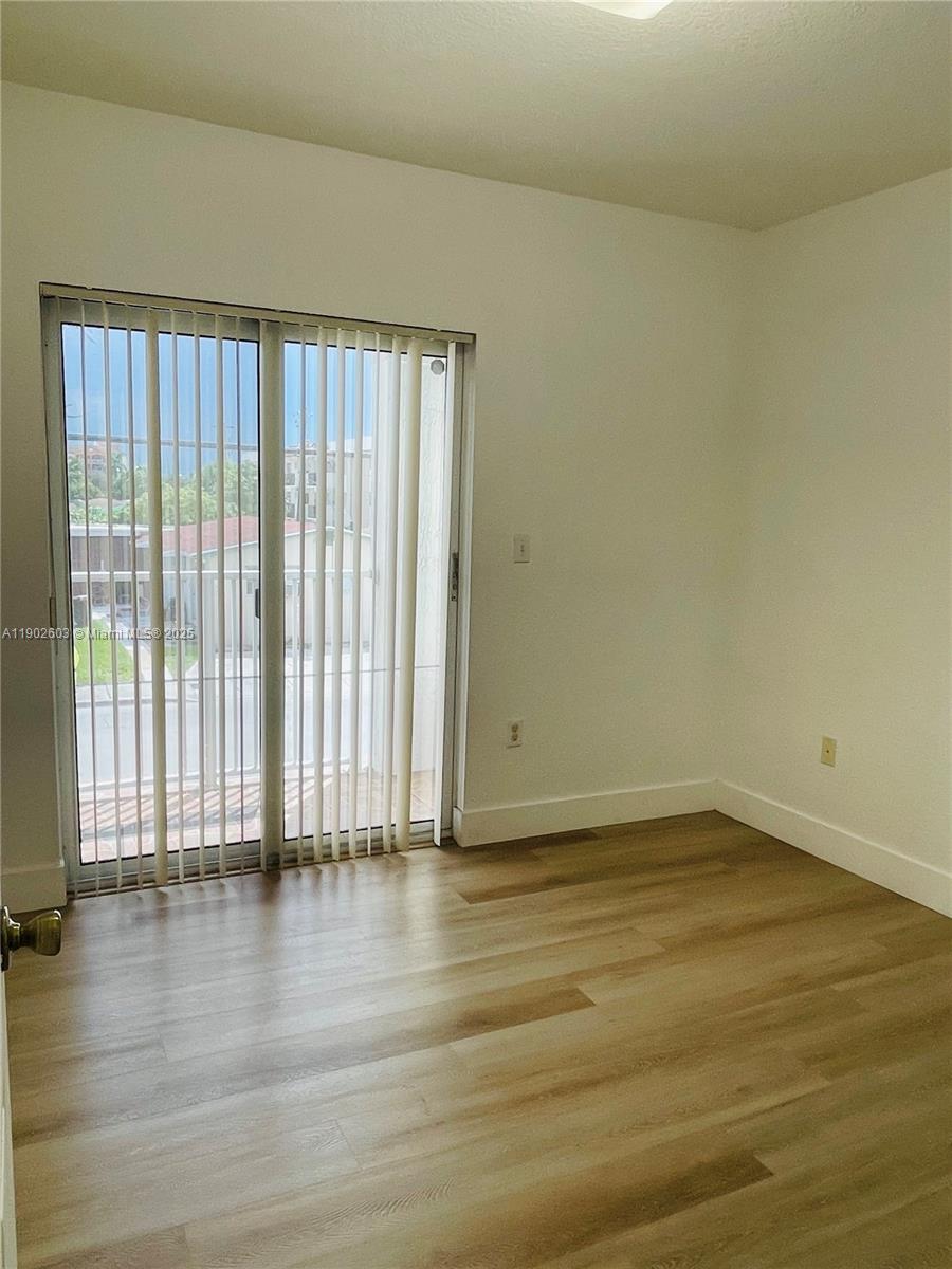 1370 West 30th Street, Unit 1370 Hialeah, FL 33012 - Photo 15 of 23 a view of an empty room with wooden floor and a window