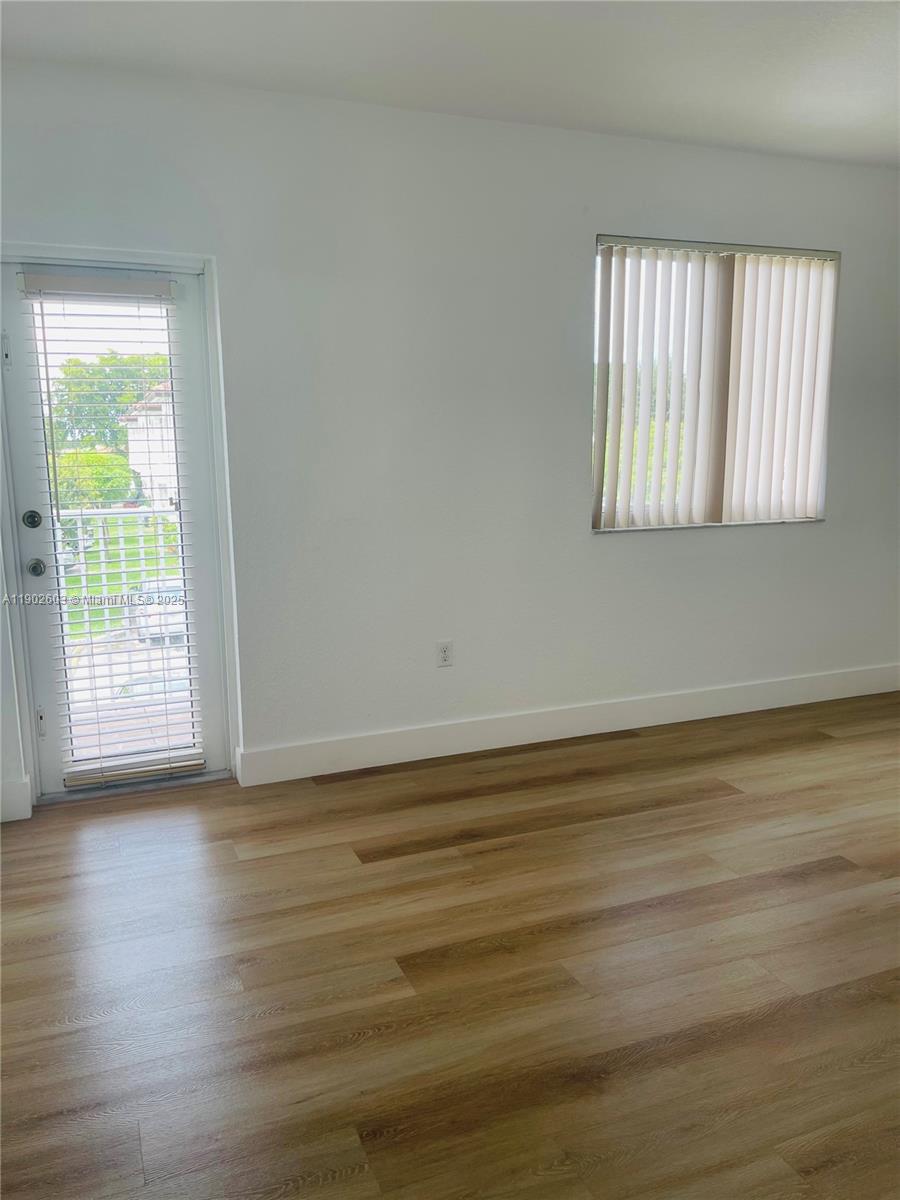 1370 West 30th Street, Unit 1370 Hialeah, FL 33012 - Photo 20 of 23 a view of an empty room with wooden floor and a window