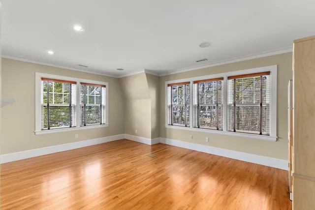 a view of an empty room with a window and wooden floor