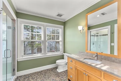 a bathroom with a granite countertop toilet a sink a mirror and next to a window