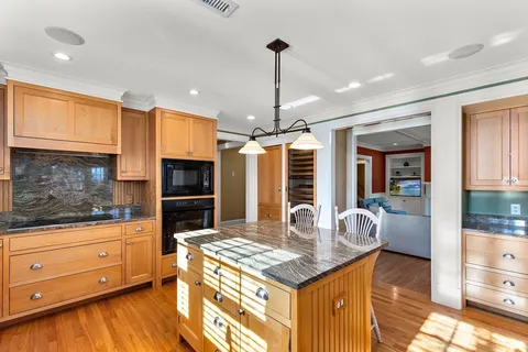 a kitchen with kitchen island granite countertop a stove and a wooden floors