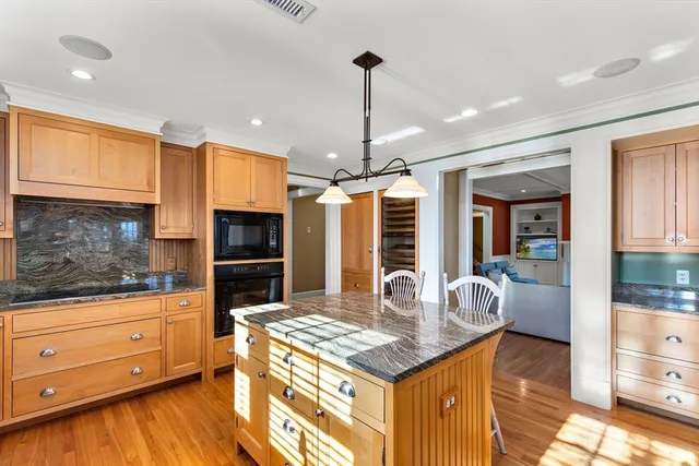 a kitchen with kitchen island granite countertop a stove and a wooden floors