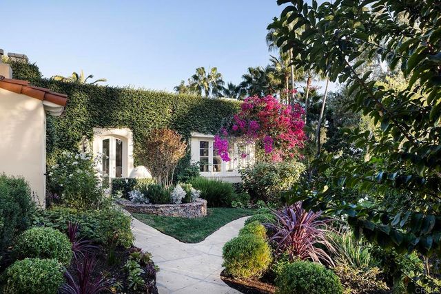 a front view of a house with a yard and potted plants