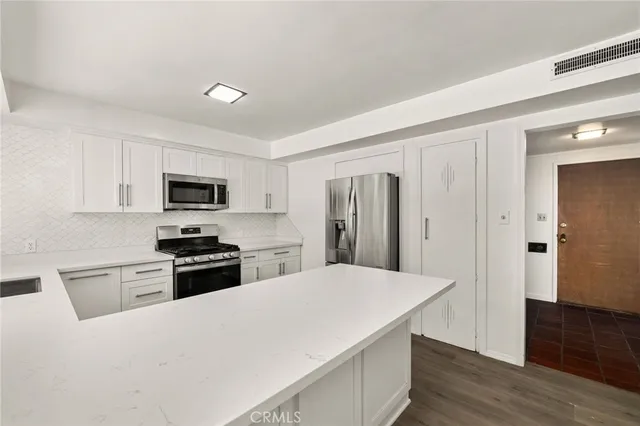 a kitchen with a refrigerator stainless steel appliances wooden floor and cabinets