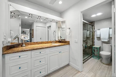 a bathroom with a granite countertop sink mirror and toilet