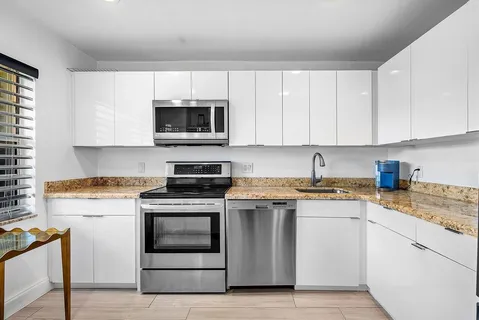 a kitchen with granite countertop white cabinets and white stainless steel appliances