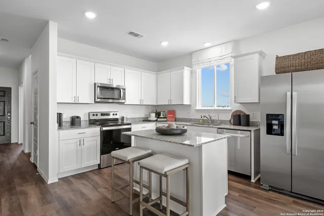 a kitchen with a refrigerator a stove top oven a sink and cabinets