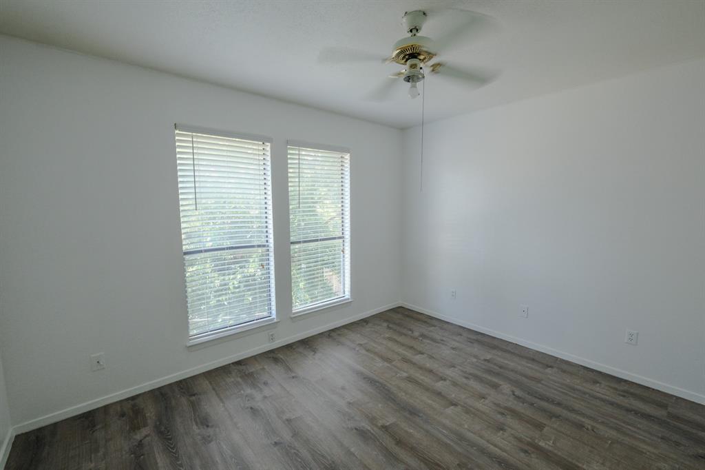 1032 McKinley Street, Unit A Benbrook, TX 76126 - Photo 12 of 14 an empty room with wooden floor chandelier fan and windows