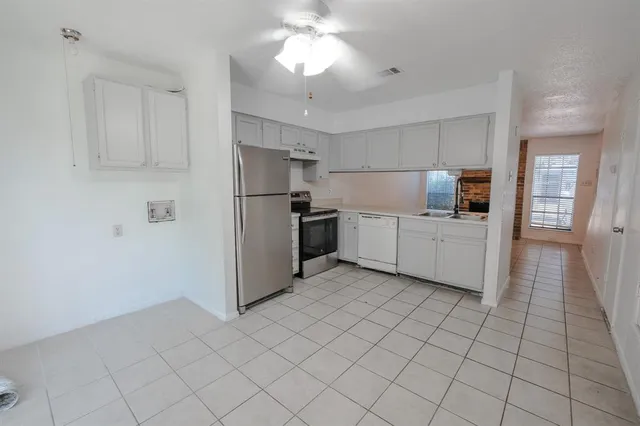 a kitchen with white cabinets a refrigerator and a counter top space