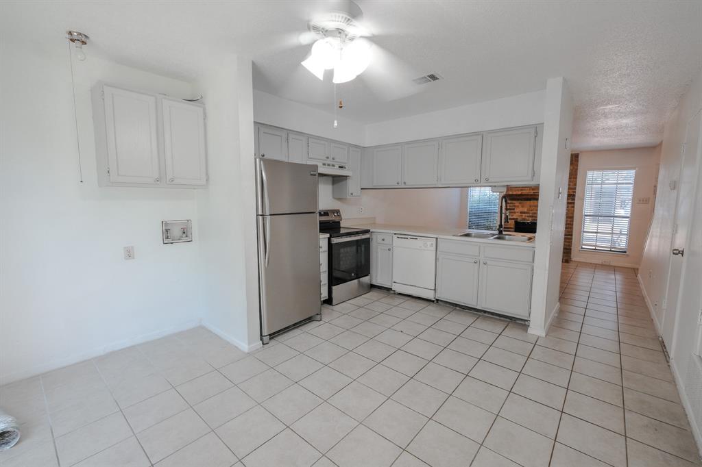 1032 McKinley Street, Unit A Benbrook, TX 76126 - Photo 5 of 14 a kitchen with white cabinets a refrigerator and a counter top space