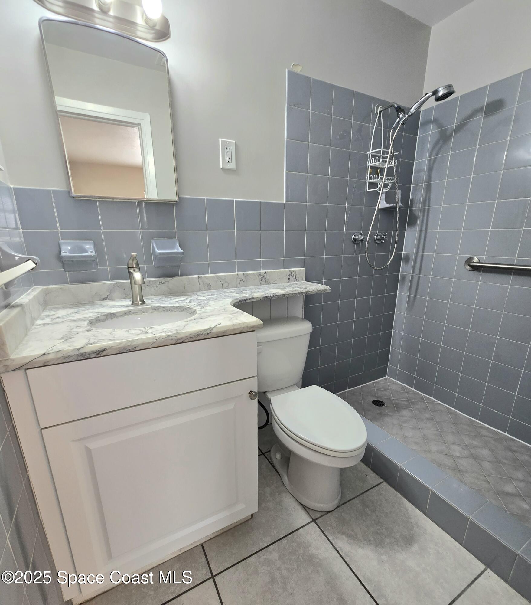 2373 Allan Adale Road Melbourne, FL 32935 - Photo 12 of 19 a bathroom with a granite countertop toilet a sink and mirror