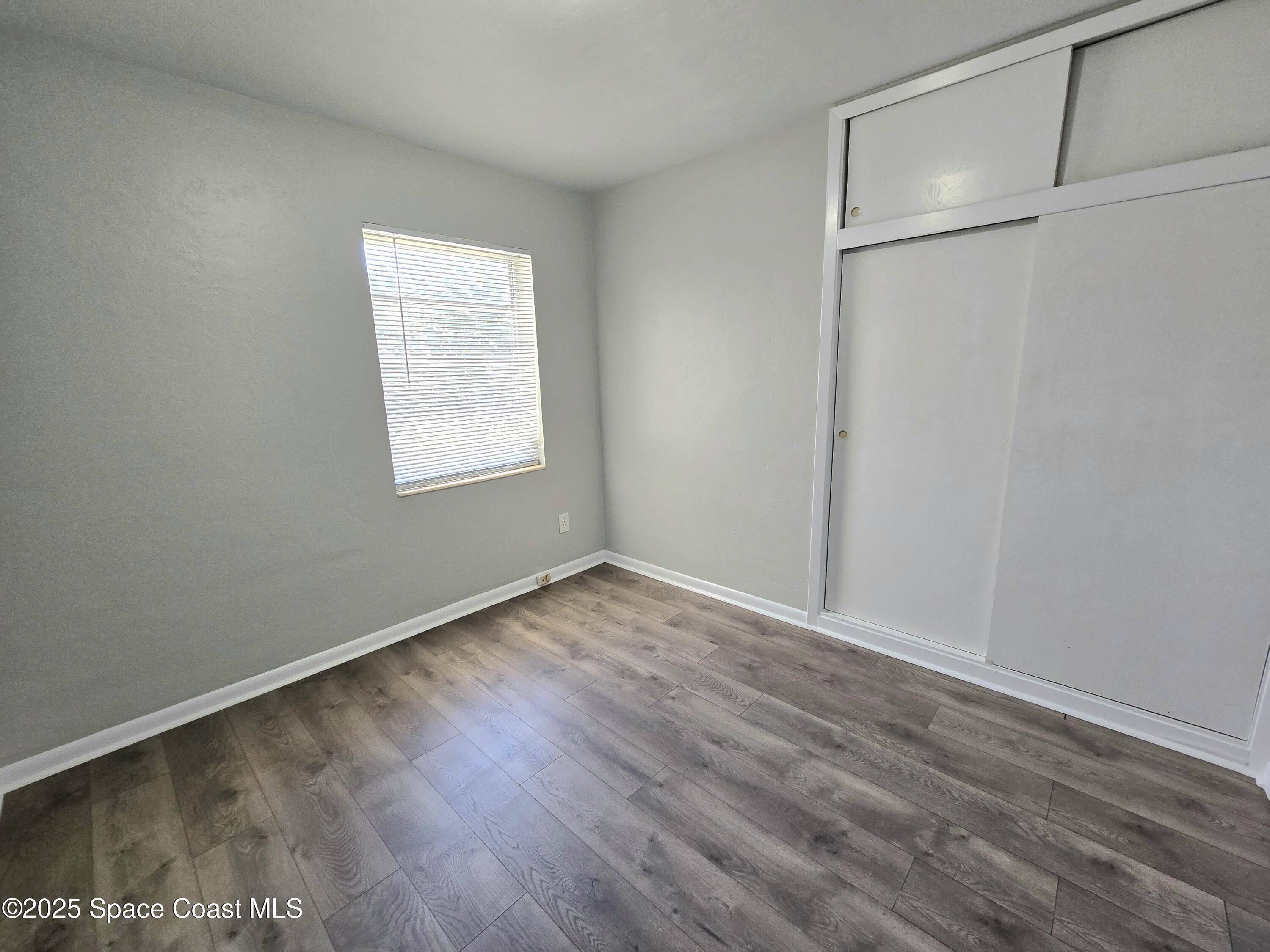 2373 Allan Adale Road Melbourne, FL 32935 - Photo 15 of 19 an empty room with wooden floor and window