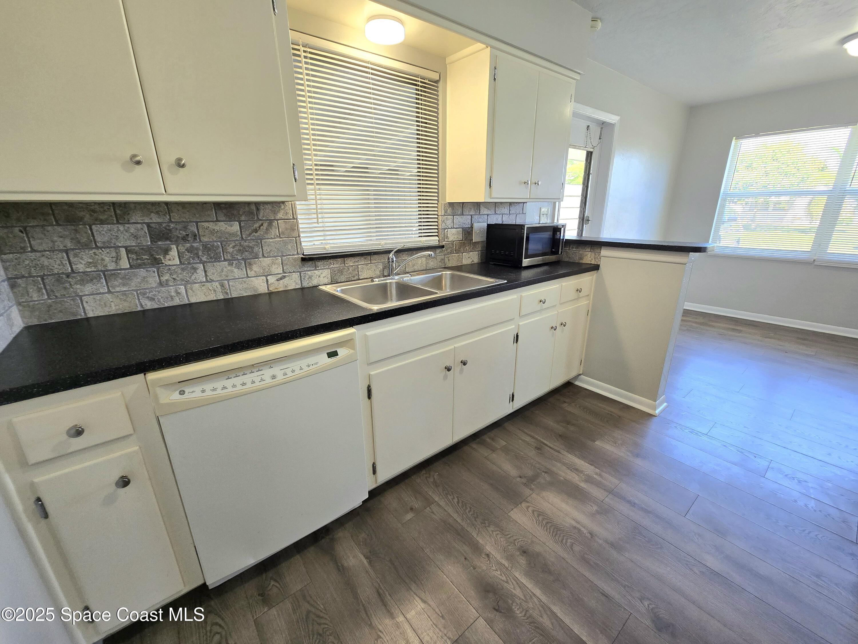 2373 Allan Adale Road Melbourne, FL 32935 - Photo 6 of 19 a kitchen with granite countertop white cabinets white appliances a sink and a window