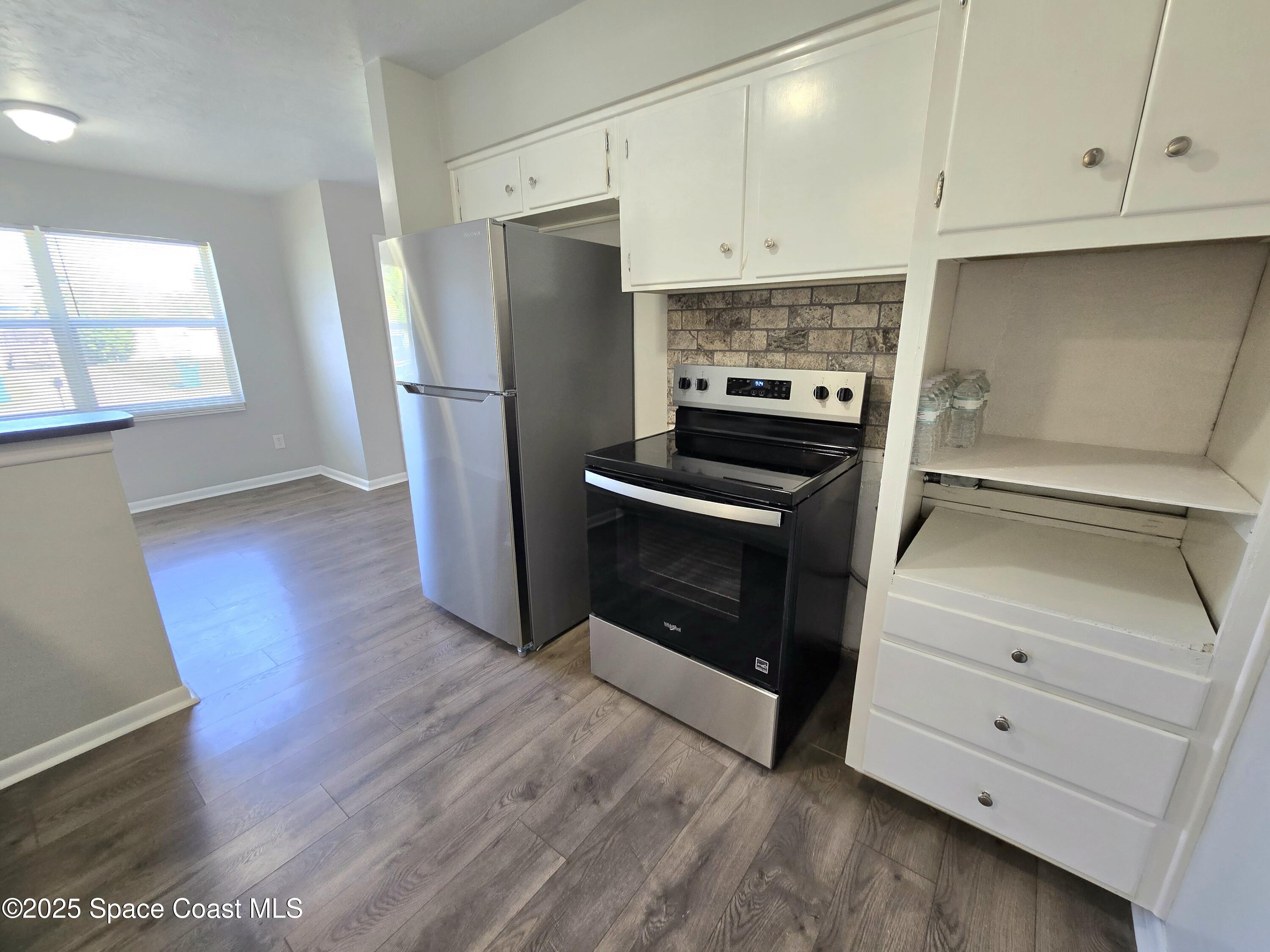 2373 Allan Adale Road Melbourne, FL 32935 - Photo 8 of 19 a kitchen with granite countertop white cabinets and stainless steel appliances