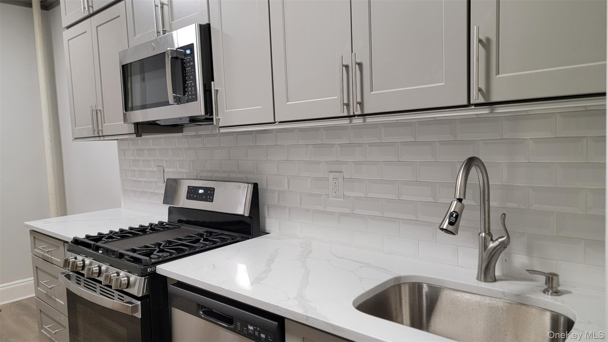 34-58 90th Street, Unit R5 Queens, NY 11372 - Photo 11 of 14 Kitchen featuring stainless steel appliances, backsplash, light stone counters, and wood finished floors