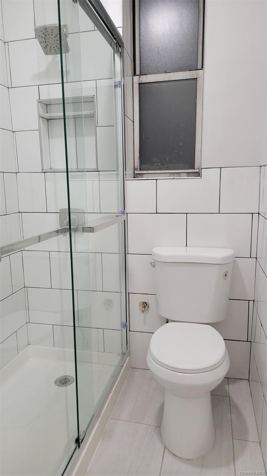 34-58 90th Street, Unit R5 Queens, NY 11372 - Photo 12 of 14 Bathroom featuring a stall shower, tile patterned floors, and tile walls