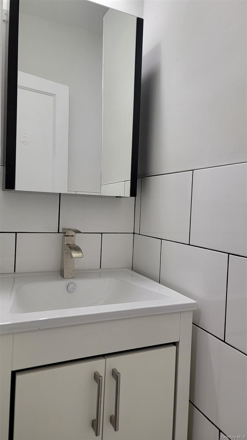 34-58 90th Street, Unit R5 Queens, NY 11372 - Photo 13 of 14 Bathroom with vanity and tasteful backsplash