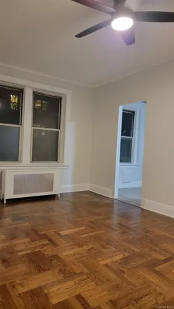 an empty room with wooden floor closet and windows