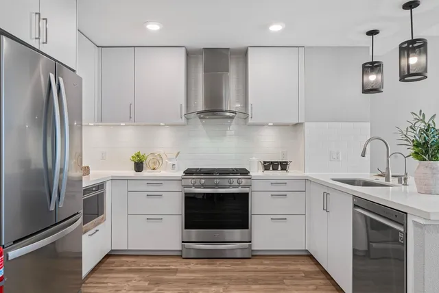 a kitchen with stainless steel appliances granite countertop a stove a refrigerator and a sink with wooden cabinets