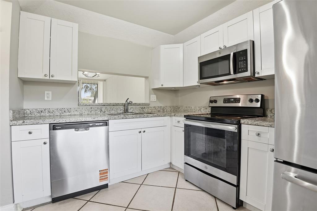 10875 Southwest 112th Avenue, Unit 202 Miami, FL 33176 - Photo 15 of 26 a kitchen with stainless steel appliances granite countertop a stove a microwave and a sink