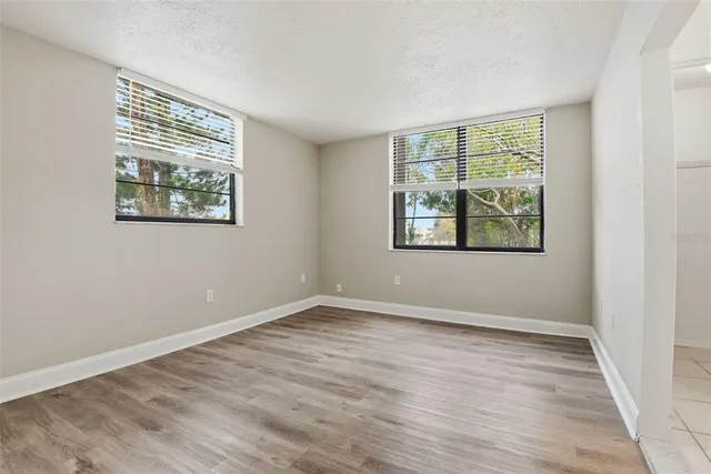 a view of an empty room with wooden floor and a window