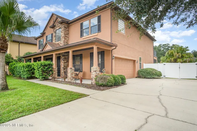 a front view of a house with a yard and potted plants