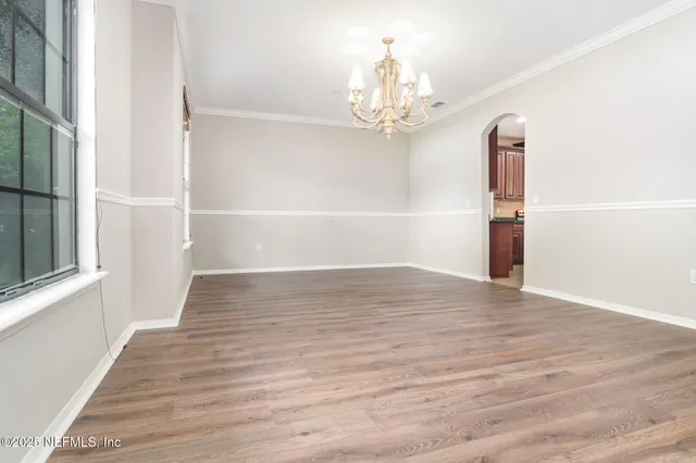 a view of a room with wooden floor chandelier and a window