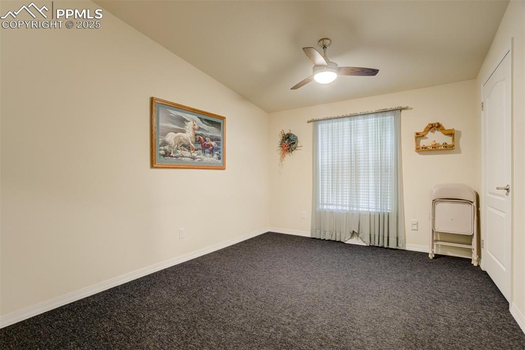 22038 County Road 2 Rush, CO 80833 - Photo 29 of 50 Unfurnished room featuring baseboards, dark colored carpet, vaulted ceiling, and ceiling fan