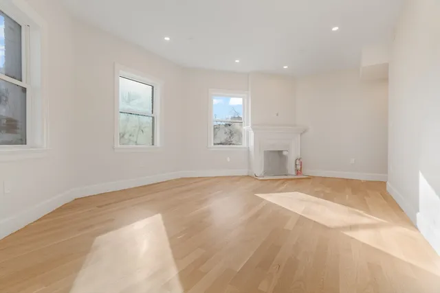 an empty room with windows and fireplace