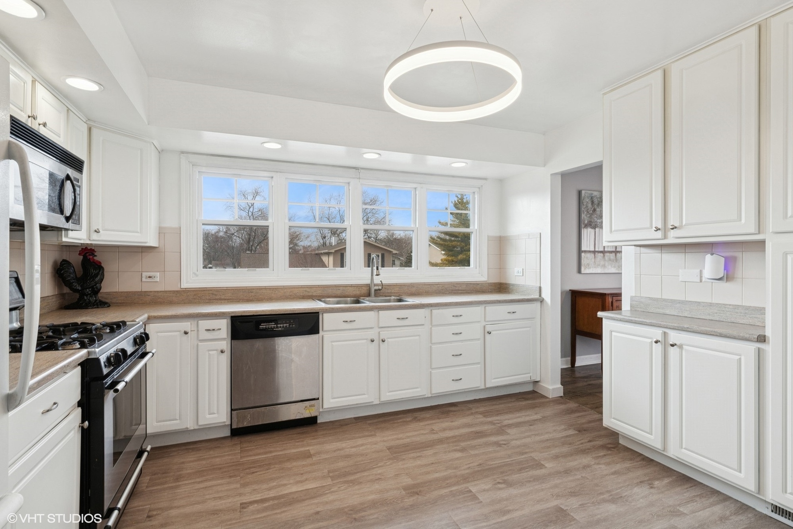 1285 Fairmont Road Hoffman Estates, IL 60169 - Photo 4 of 21 a kitchen with granite countertop a stove top oven a sink and white cabinets with wooden floor