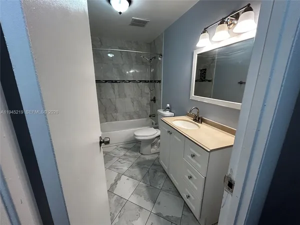 a bathroom with a granite countertop sink mirror vanity and toilet
