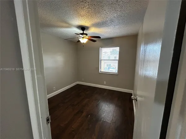 an empty room with wooden floor fan and windows