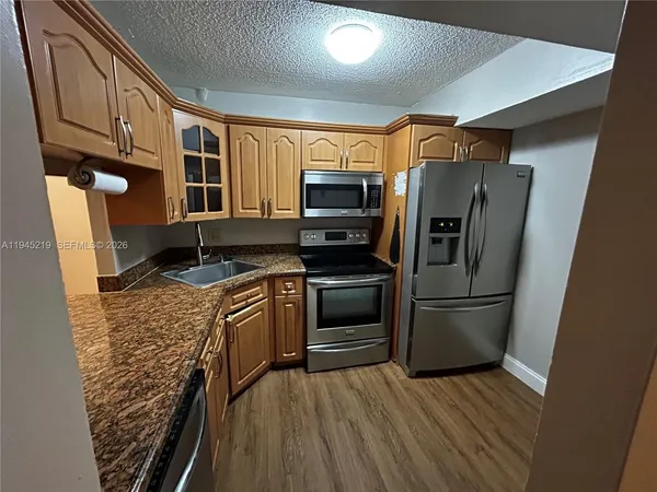 a kitchen with stainless steel appliances granite countertop a refrigerator a stove top oven a sink and dishwasher