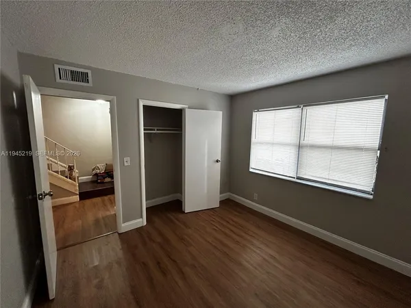 a view of a livingroom with wooden floor and a kitchen