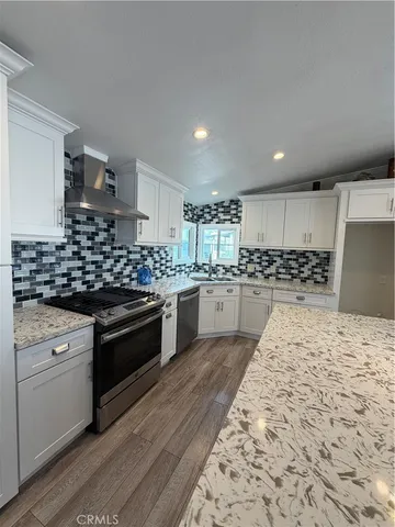 a kitchen with stainless steel appliances kitchen island granite countertop a stove a sink and a refrigerator
