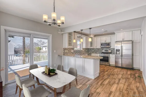 a kitchen with kitchen island granite countertop a stove a sink dishwasher a dining table and chairs with wooden floor