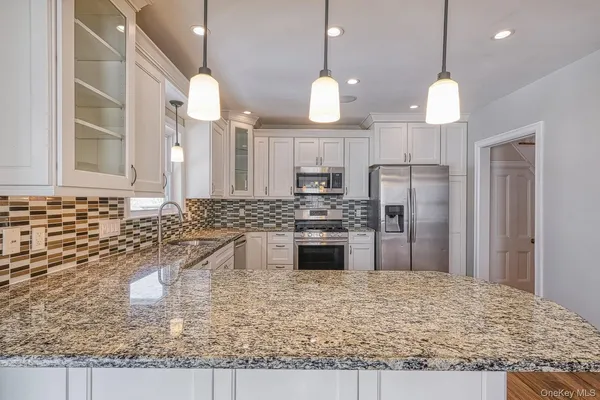 a kitchen with stainless steel appliances granite countertop a sink a refrigerator and a stove