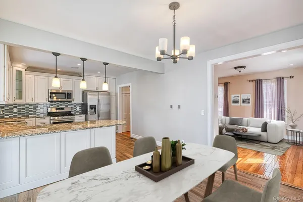 a kitchen with stainless steel appliances kitchen island granite countertop a table chairs in it and wooden floors