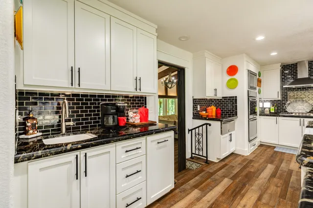 a kitchen with stainless steel appliances kitchen island granite countertop a table chairs and a refrigerator