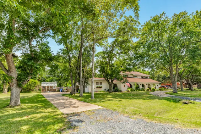 a front view of a house with garden and trees