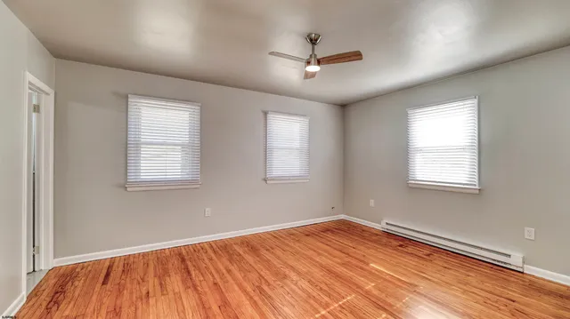 a view of empty room with wooden floor and fan