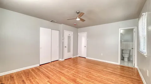 a big room with wooden floor and bathroom view